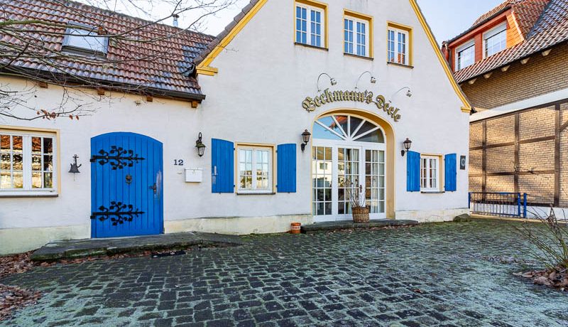 Charmanter historischer Hof mit malerischem Eingangsbereich und charakteristischen blauen Fensterläden – einladend und idyllisch gelegen.