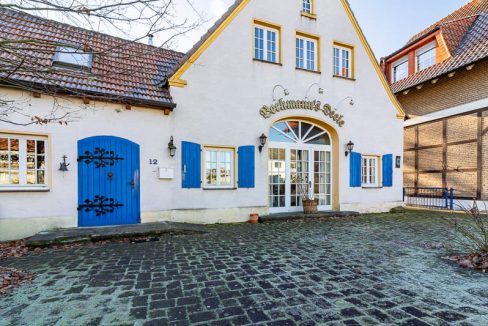 Charmanter historischer Hof mit malerischem Eingangsbereich und charakteristischen blauen Fensterläden – einladend und idyllisch gelegen.