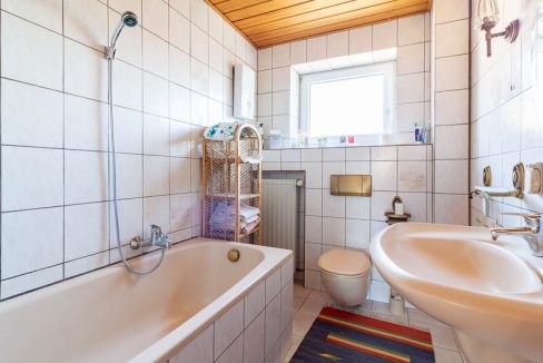 Helles Badezimmer mit Badewanne, praktischem Stauraum und Tageslicht – eine einladende Wohlfühloase.